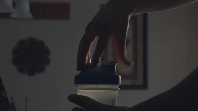 Screwing the cap onto a shaker cup with a protein shake inside.