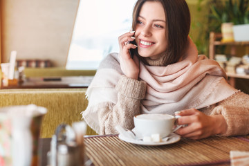 Beautiful young girl using phone in cafe