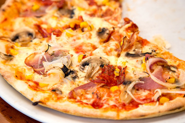 Close up shot of pizza with prosciutto and mushrooms