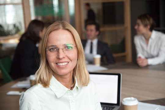 Smiling middle-aged businesswoman looking at camera at group meeting, friendly female company executive manager or team leader, happy business coach posing in office, woman boss head shot portrait