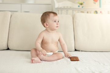 Fototapeta premium Toned photo of cute toddler boy sitting on sofa with smartphone