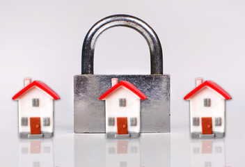 Composition with a big lock and miniature houses. Concept of closed access or arrest to house or dwelling.