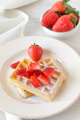 Healthy breakfast table with  belgian waffles and strawberries on a rustic table
