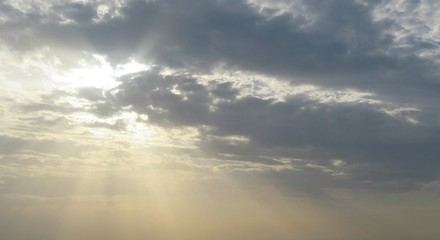 Sunset view over the city, the sun rays shining through the dark clouds, natural sky background