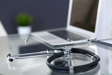 Stethoscope, prescription medical form lying on glass table with laptop computer. Medicine or pharmacy concept. Medical tools at doctor working table