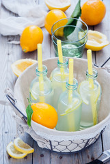 Basket organic lemon lemonade bottles on a wooden background