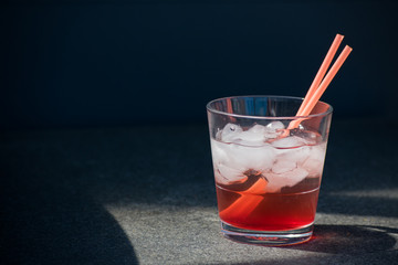 Red Cocktail Lemonade Glass Ice Cubes Straws Isolated Sun Summer Drink Black background Stone