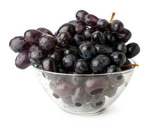Bunch of blue ripe grapes in glass plate on a white background.