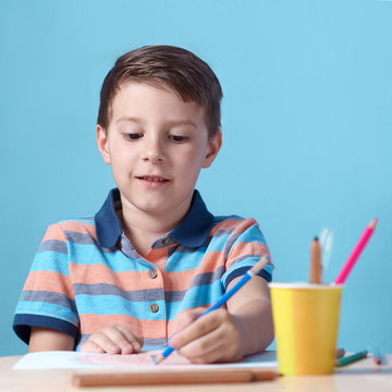 Caucasian boy spending time drawing with colorful pencils at home.