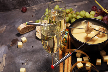 Obraz na płótnie Canvas Gourmet Swiss fondue dinner on a winter evening with assorted cheeses on a board alongside a heated pot of cheese fondue