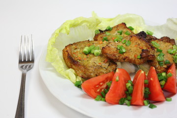 fried pieces of pork chop with lettuce, tomatoes and chives