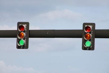 Two Green Traffic Lights Against Noon Day Sky