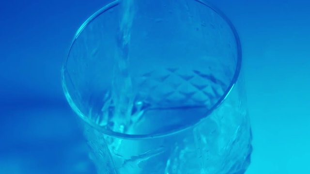 slow motion fill water in a transparent glass. blue color its no efect, its a blue lamp
