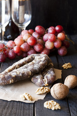 Snacks for wine, cheese with mold, pink grapes, walnuts and jerked dry sausage