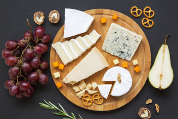 Cheese plate. Assorted cheeses with fruits, walnuts and pretzels. Food for wine. Top view.