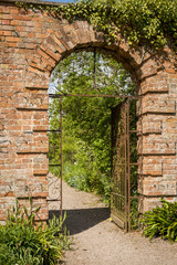 Arched doorway with metal gate in walled garden Spetchley Gardens Worcester