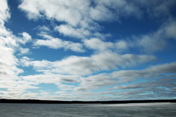 The blue sky in white clouds and the lake covered with ice