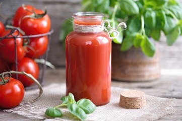 Tomato juice in glasses and tomato on wooden table on wooden background