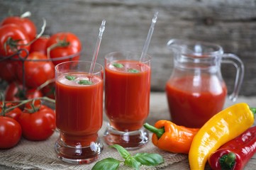 Tomato juice in glasses and tomato on wooden table on wooden background