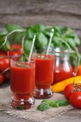 Tomato juice in glasses and tomato on wooden table on wooden background