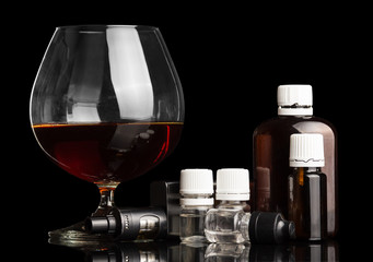 Glass of alcohol, electronic cigarette and liquid for vaping, isolated on black
