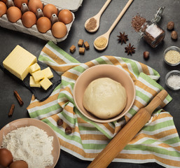 Set of products and spices, finished dough in bowl on towel on gray surface