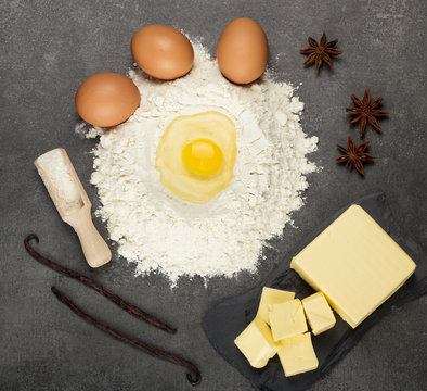 Hill of flour with broken egg for dough kneading, oil and spices on work surface