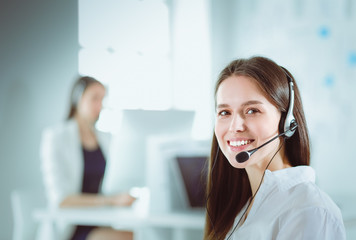 Smiling businesswoman or helpline operator with headset and computer at office