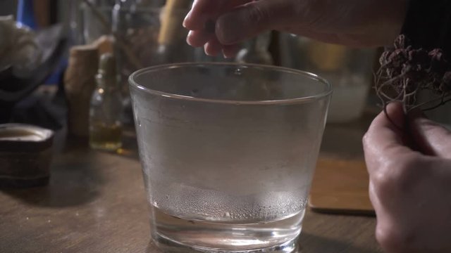 Woman's hands put dried berries and secret powder into the glass with hot water