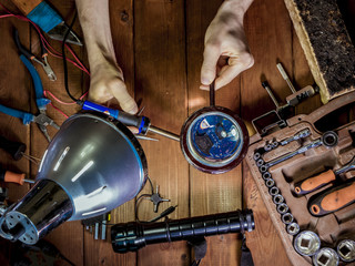 engineer with magnifier in hands making a board with soldering iron