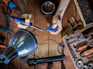 engineer with magnifier in hands making a board with soldering iron
