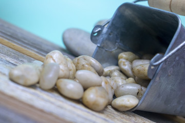 A tin full of beautiful river rocks spills over on a distressed wood backdrop. Beautiful blue background leaves room for text! 