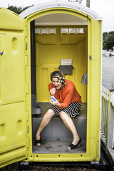 Woman hiding in porta potty trying to apply her make-up and do her hair woman hiding in bathroom trying to apply her make-up and do her hair