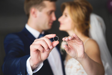 The bride and groom are holding wedding rings. Wedding rings close-up. Focus on wedding rings, unfocus the bride and groom