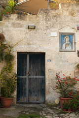 Italy, Southern Italy, Region of Basilicata, Province of Matera, Matera. The town lies in a small canyon carved out by the Gravina.Stone Building with plaque of Madonna.