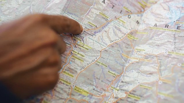 Close-up of traveler&rsquo;s hand exploring the map in the forest.