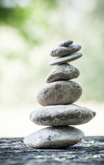 Fototapeta na wymiar closeup of stones balance on wooden table on green blurred background