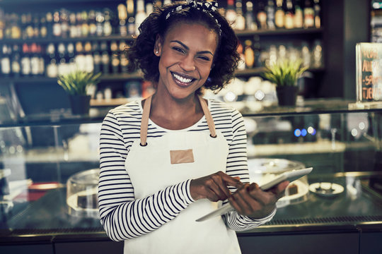 Young African entrepreneur standing in her cafe using a tablet