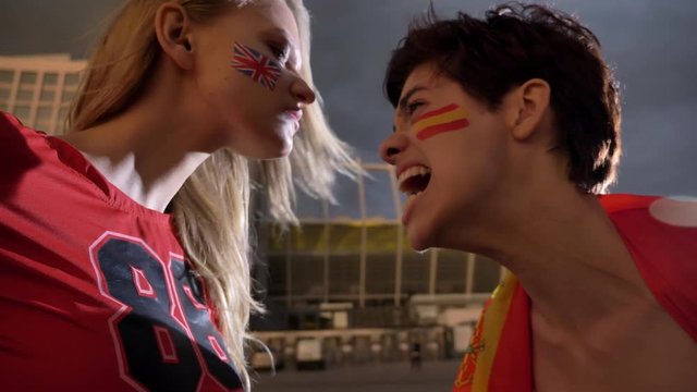 Two young girls, football fans, England against Spain, confrontation, screaming, stadium in the background 50 fps