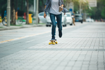 Fototapeta premium woman skateboarding with coffee cup in hand on city street