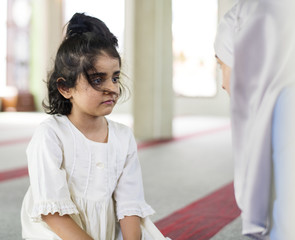 A little girl in the mosque with her mother during Ramadan