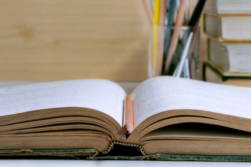 Open hardback and textbook stacked on the table background.