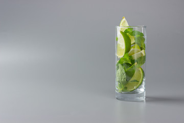 Sliced lime with mint in highball on a gray background.