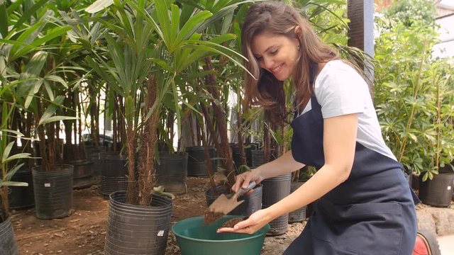 Young woman digging dirt in nursery