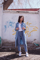 Beautiful girl posing, the old painted wall on the background. Lifestyle.