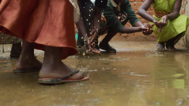 African children washing their hands in a puddle