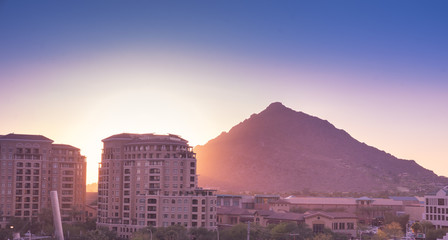 Sun setting over Scottsdale, Arizona waterfront area with Camelback Mountain glowing.