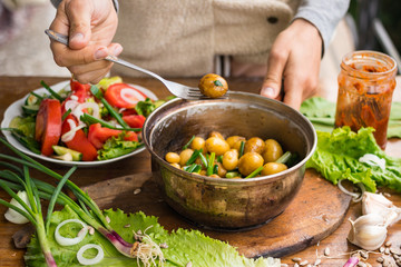 Woman hands holds new potato cooked in pot and served with olive oil, butter, herbs and onion sprouts. Raw vegan vegetarian healthy food. Organic farm products