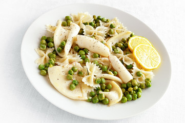 seafood with pasta and pea decorated with lemon rings and sprinkled with black pepper