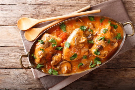 Tasty rustic French food: chicken with mushrooms stewed in sauce close-up. horizontal top view